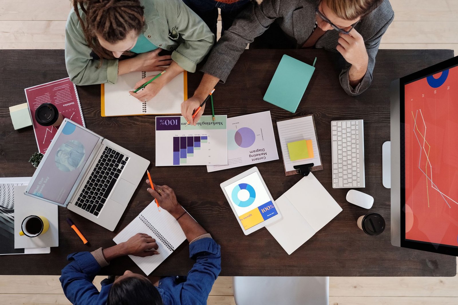 A team working together around a table with laptops, charts and notes, seen from above