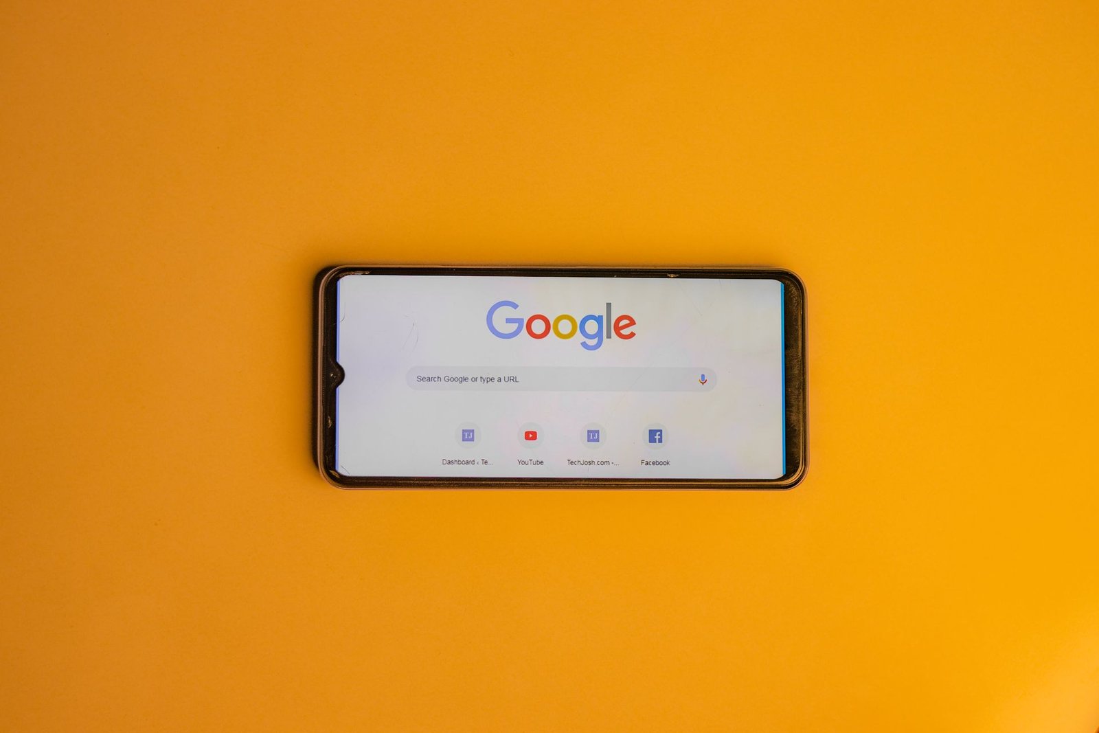 A smartphone showing the Google search page on a yellow background