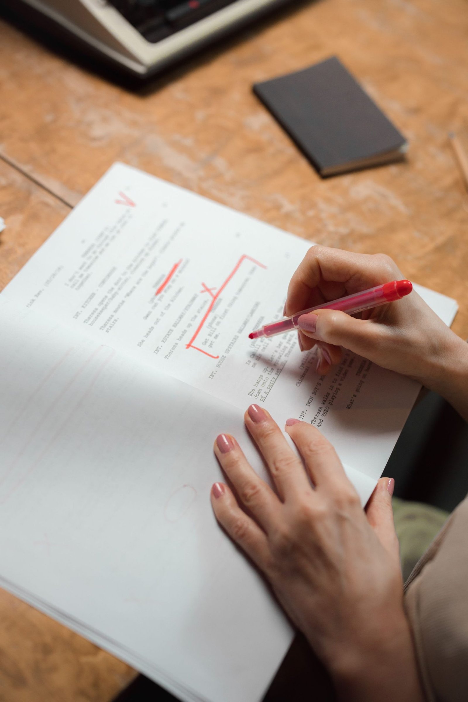 A hand correcting a printed page with a red pen