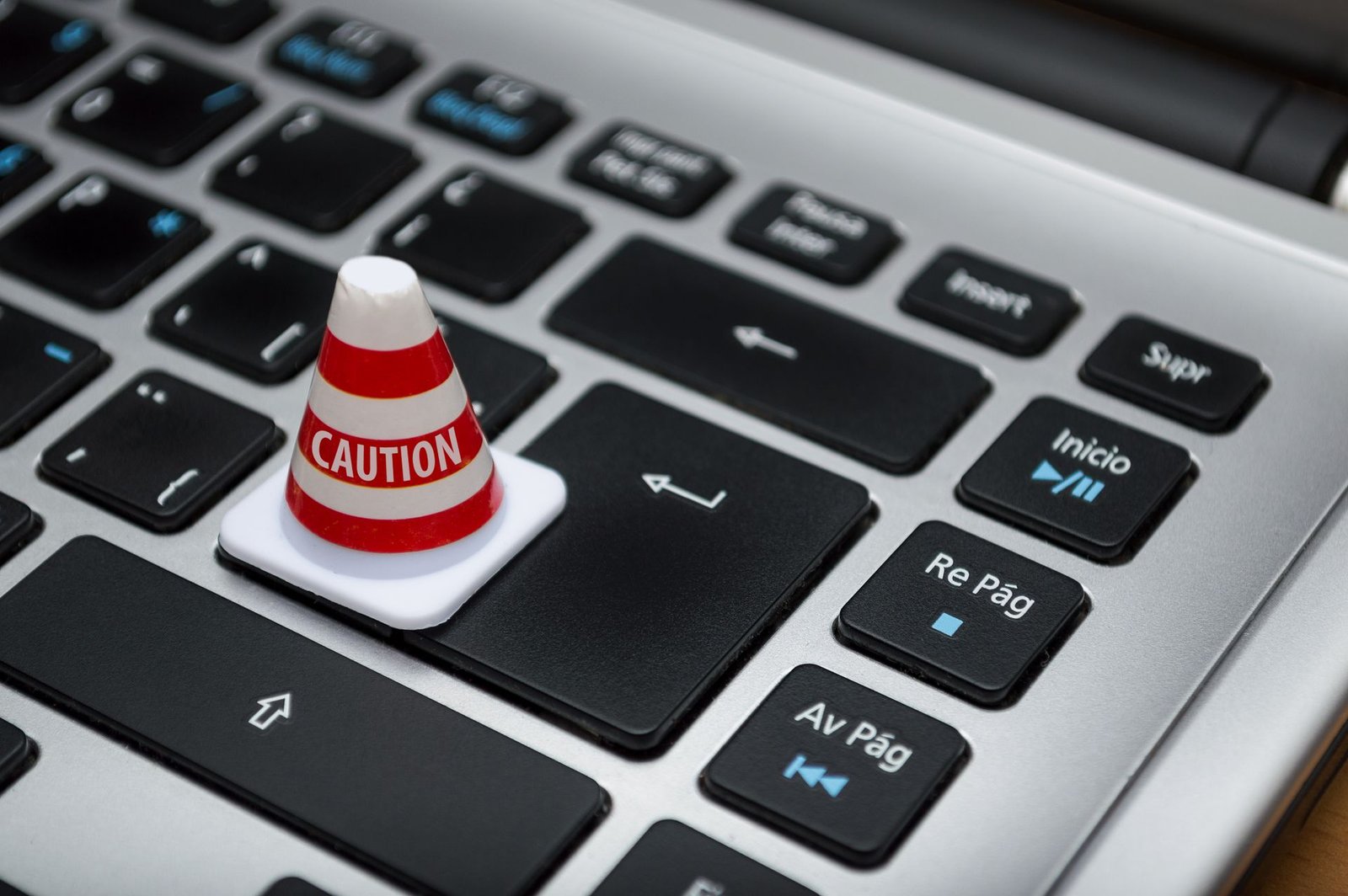 A small caution cone standing on a laptop keyboard