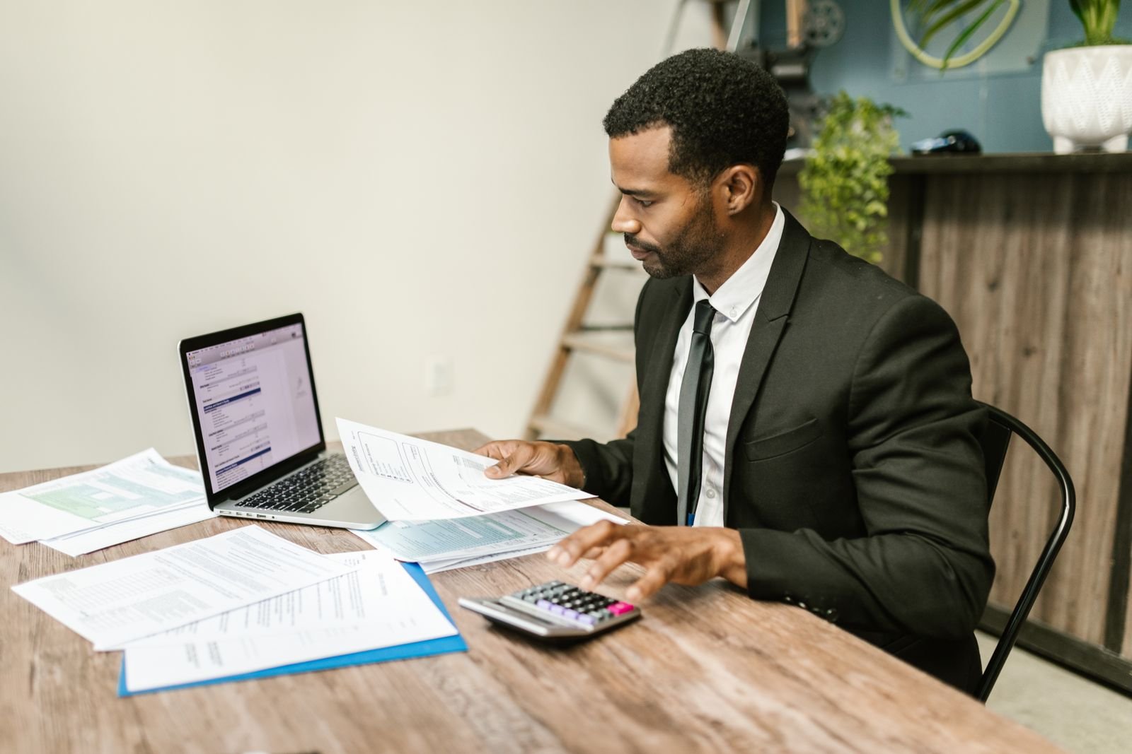 An agency owner at a desk going through invoices and figures with a calculator