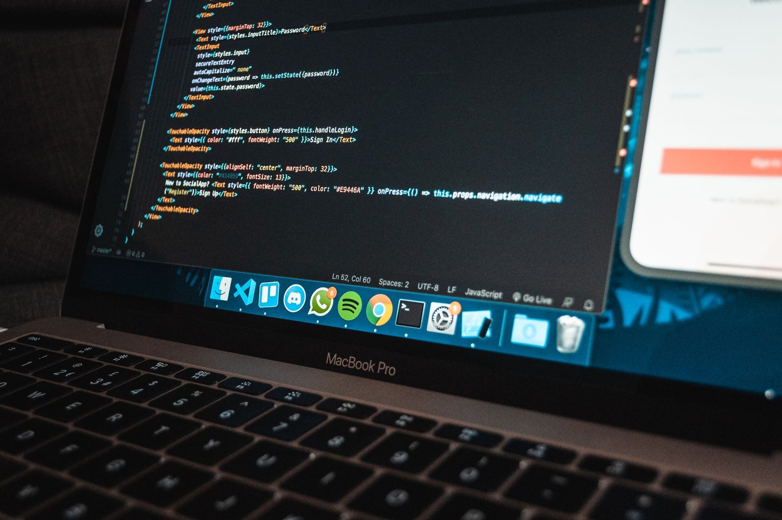 A laptop screen showing code next to a phone on a desk