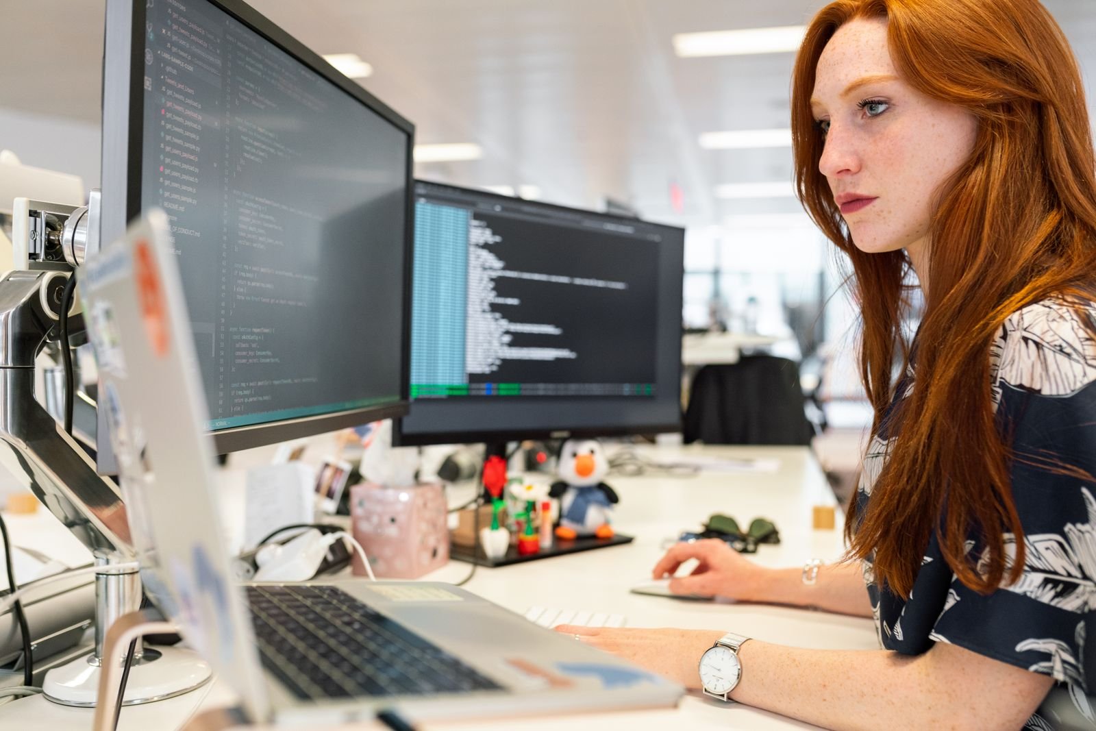 Developer reviewing code on her screens