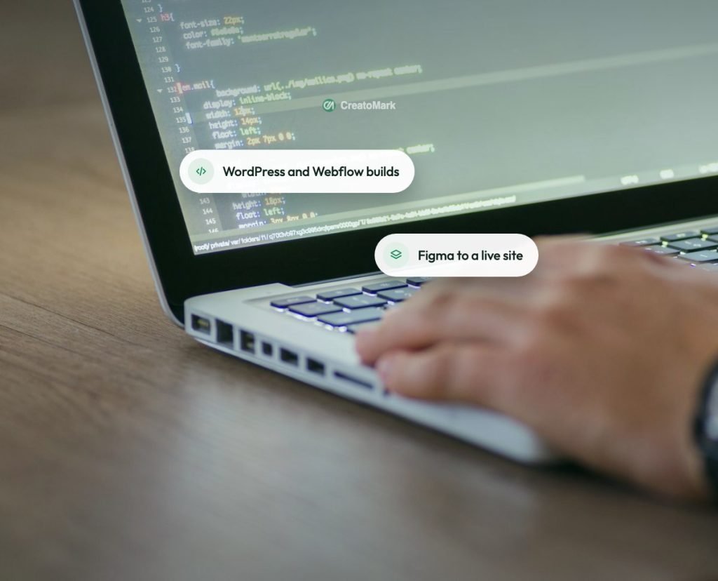 Hands typing code on a laptop at a wooden desk